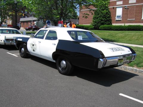 1991 Ford LTD Crown Victoria - black-and-white four-door police sedan lettered POLICE with a shield door emblem parked on a street at a show.
