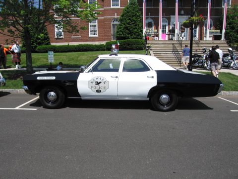 1991 Ford LTD Crown Victoria - Side profile of a black-and-white Newark Police four-door sedan with a circular badge emblem parked at an outdoor event.