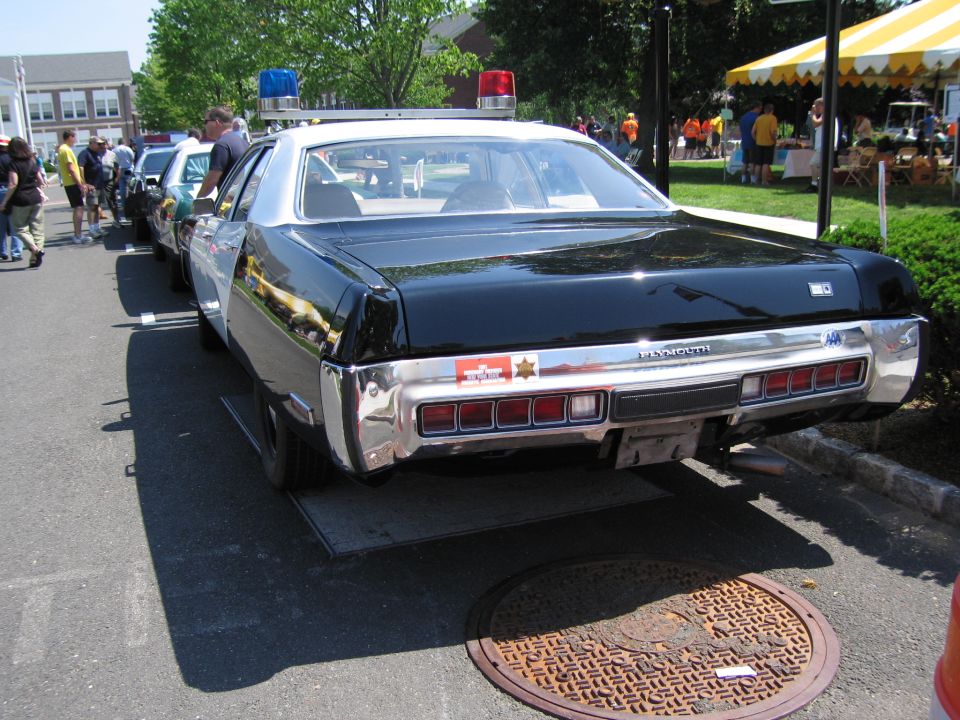 Rear view of black and white Plymouth police sedan with red roof beacons