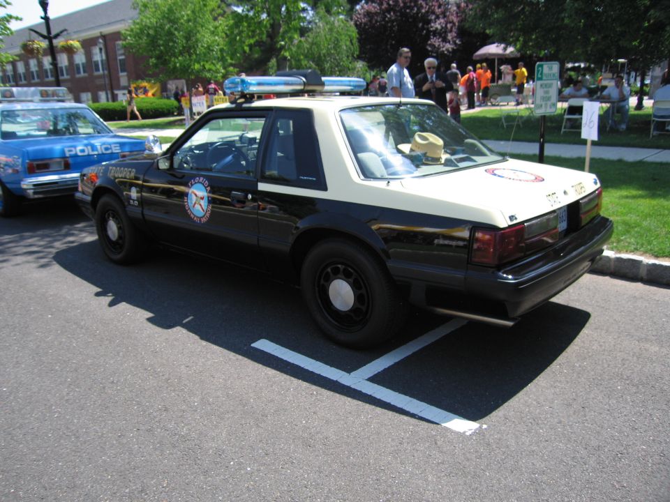 Rear three-quarter of black and tan police Mustang coupe with roof lightbar