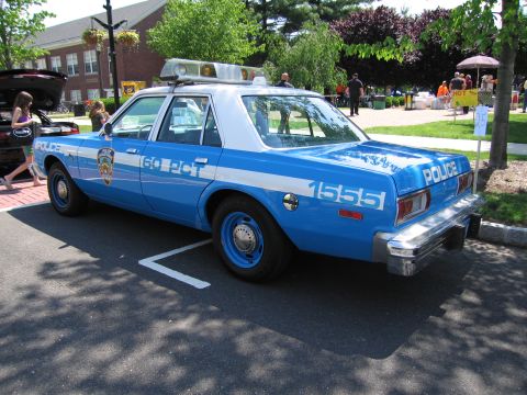 1991 Ford LTD Crown Victoria - blue-and-white four-door police sedan lettered POLICE and 60 PCT, numbered 1555, parked on pavement at a car show.