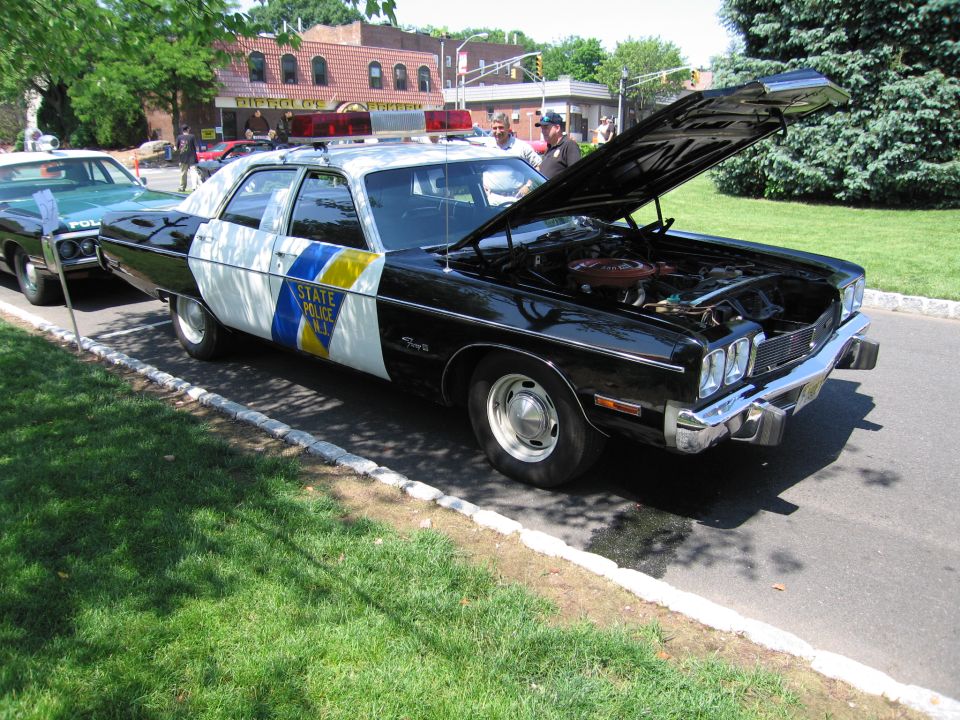 Black and white New Jersey State Police sedan with hood open at a car show