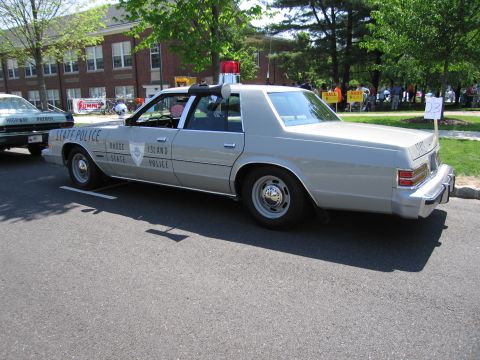 1991 Ford LTD Crown Victoria - silver Rhode Island State Police four-door sedan parked along a curb at a car show.