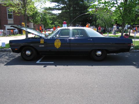 1991 Ford LTD Crown Victoria - dark blue vintage police sedan with a gold door emblem and open trunk, shown in profile at an outdoor display.