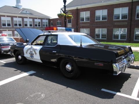 1991 Ford LTD Crown Victoria - Rear three-quarter view of a black-and-white Highway Patrol sedan with its hood raised, parked at a car show.
