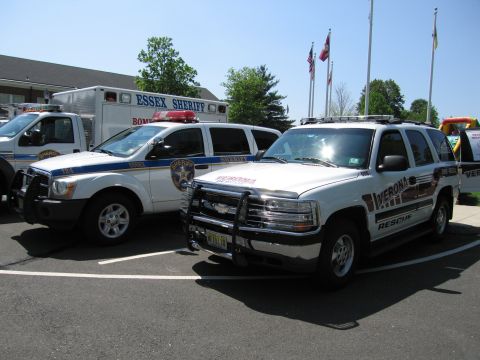 1991 Ford LTD Crown Victoria - White Essex Sheriff and Verona Rescue SUVs parked side by side near flagpoles and an emergency-services building.