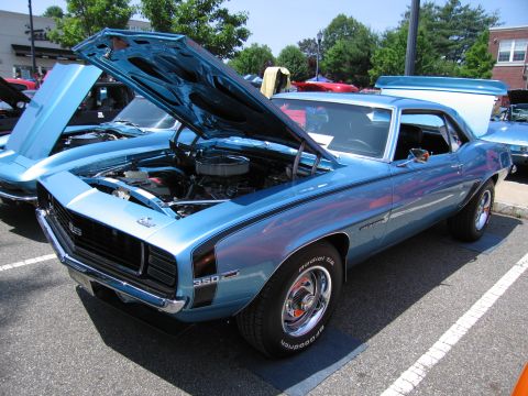 1991 Ford LTD Crown Victoria - light blue Chevrolet Camaro with raised hood displayed among other cars at an outdoor car show.