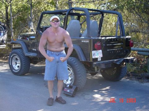 1989 Ford Bronco - A man poses with his Jeep Wrangler, which has a custom bumper and roll cage.
