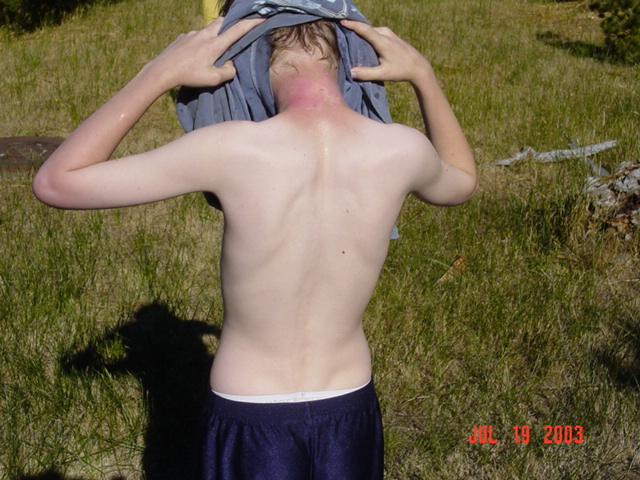 Person from behind removing a shirt in a grassy field