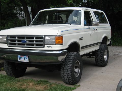 1987 Ford Bronco - A white 1987 Ford Bronco is shown with a lifted suspension and large off-road tires.