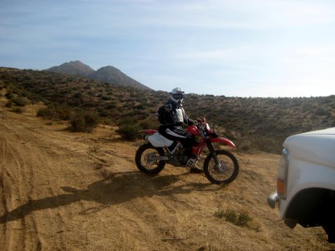 1996 Ford Bronco - Rider and dirt bike on a hill, with a white truck nearby.