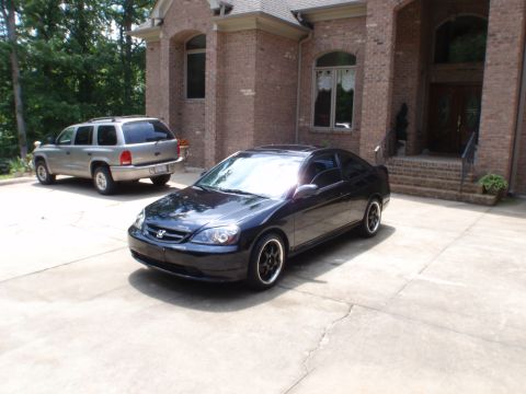 1996 Ford Bronco - A black coupe and a silver SUV are parked in a driveway outside a large brick house.
