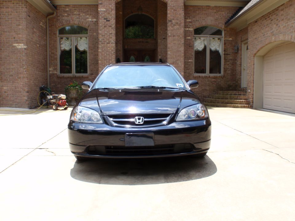 Black Honda Civic coupe front view on a driveway in front of a brick house