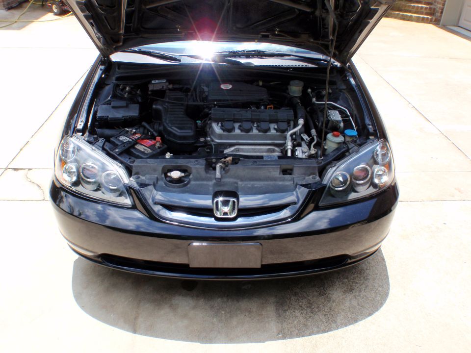 Black Honda coupe front with hood open showing engine bay and clear projector headlights