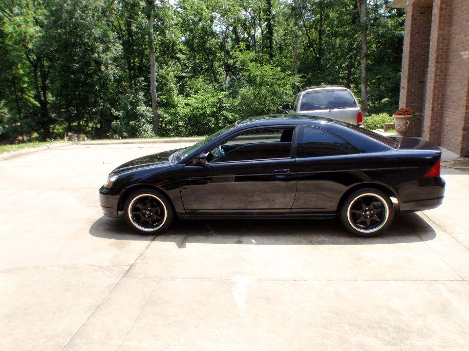 Passenger-side profile of a black Honda Civic coupe on a concrete driveway