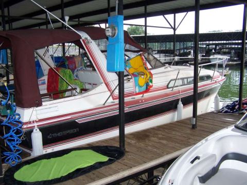 1979 Ford F-150 - A Thompson boat is docked under a covered slip, with a Bart Simpson decal visible on its side.