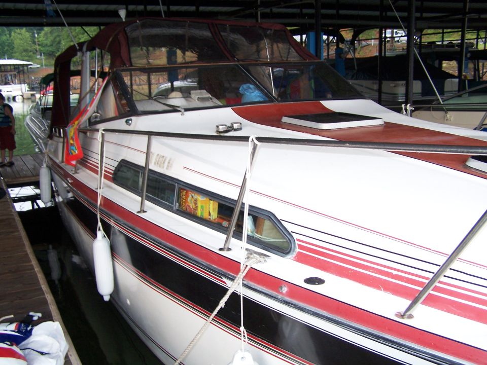 Boat docked under a cover, showing its white hull with red and black stripes