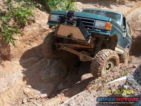 1990 Ford Bronco - Green 1990 Ford Bronco tackling a difficult off-road obstacle on a sunny day.