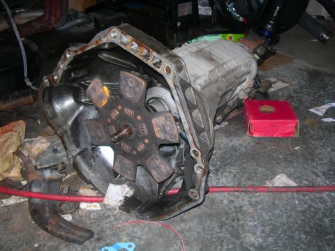 1984 Ford Bronco - A vehicle's transmission and clutch assembly are shown disassembled on a concrete floor, possibly in a workshop or garage.