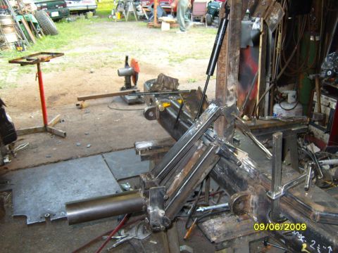 1989 Ford Bronco - Metal fabrication equipment is shown in a workshop setting with other vehicles and tools visible in the background.