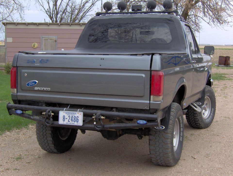 Gray 1987 Ford Bronco with aftermarket bumper and roof lights, viewed from the rear