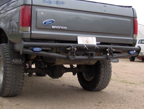 1987 Ford Bronco - Gray 1987 Ford Bronco rear view, showing aftermarket bumper and tow hitch. Another vehicle is parked nearby.