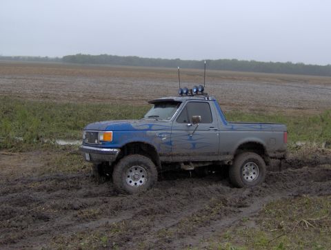 1987 Ford Bronco - This 1987 Ford Bronco is navigating a muddy terrain under an overcast sky.