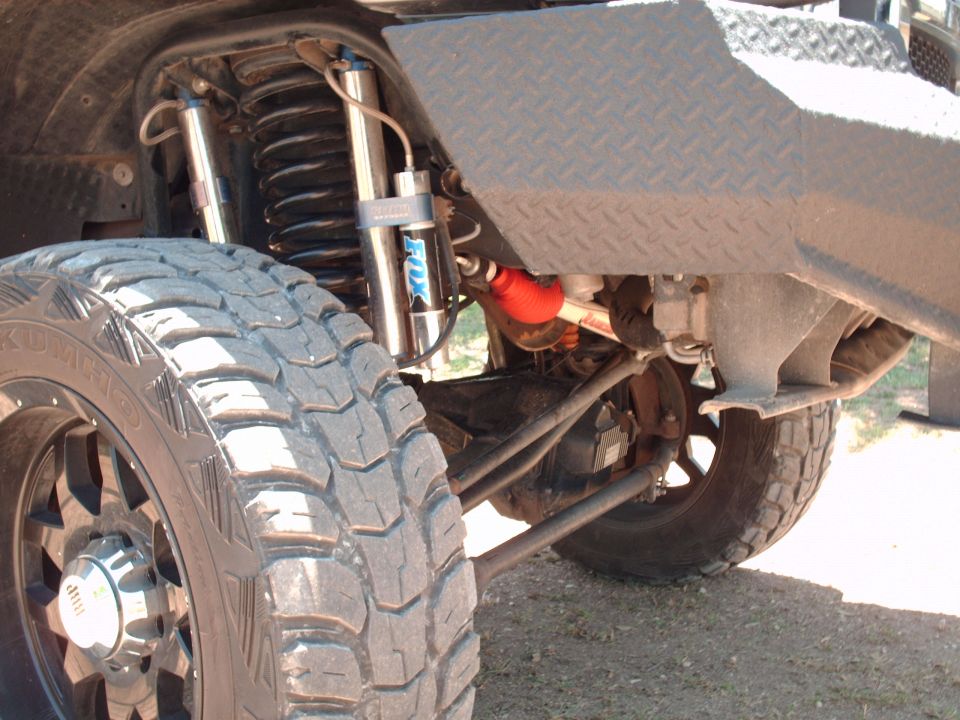 Close-up of a large off-road tire and front suspension with Fox shocks