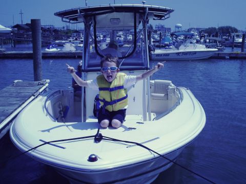 1979 Ford F-250 - A child poses excitedly on a boat docked in a marina with other boats in the background.