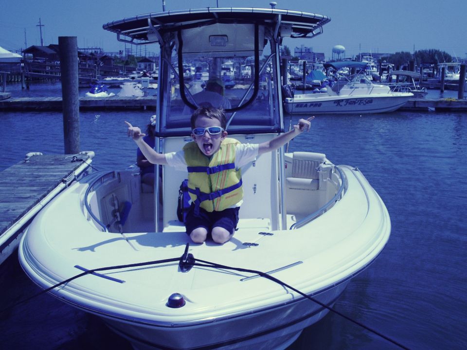 Child in life vest on a boat in a marina