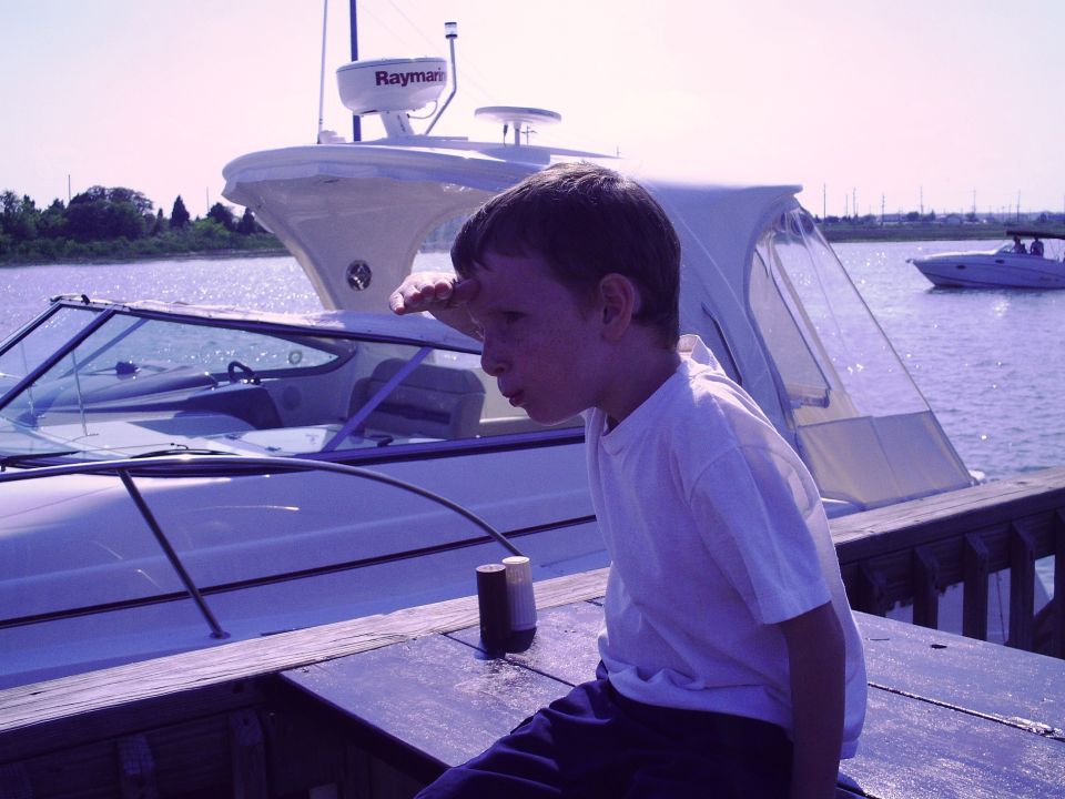 Boy gazes at boats on the water