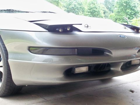 1995 Ford Probe - The front of a silver Ford Probe is shown, its distinctive pop-up headlights and fog lights.