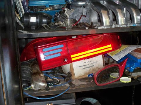 1995 Ford Probe - Car parts including tail lights and a side mirror are stored on shelves.