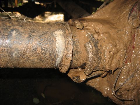 1991 Ford Bronco - Close-up of a heavily mud-caked vehicle axle and differential, suggesting off-road use.