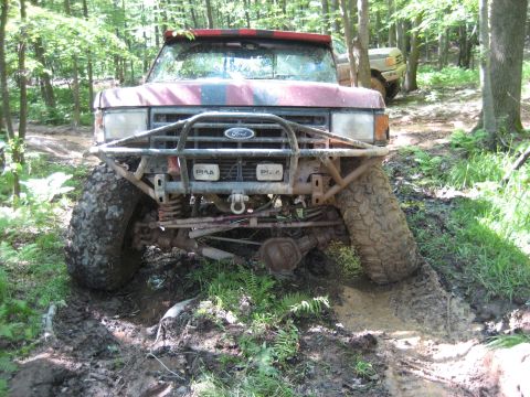 1991 Ford Bronco - This modified Ford Bronco tackles a challenging muddy obstacle on an off-road trail.