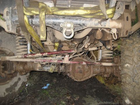 1991 Ford Bronco - The underside of a heavily soiled vehicle is shown, with visible suspension parts and tow straps.
