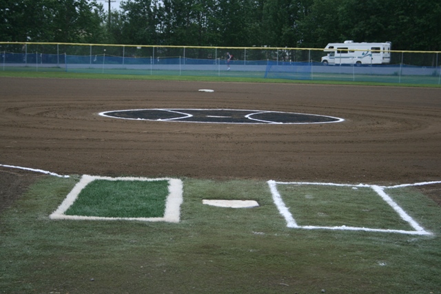 RV motorhome parked behind a baseball field fence