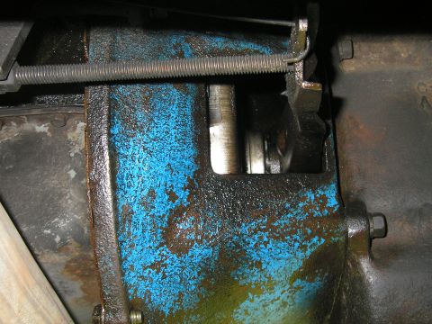 1979 Ford Bronco - Detail of a greasy blue metal component with a spring and linkage, likely part of a vehicle's drivetrain.