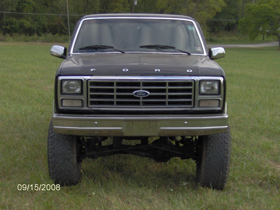 Dark gray lifted 1980s Ford F-Series pickup front view in a field