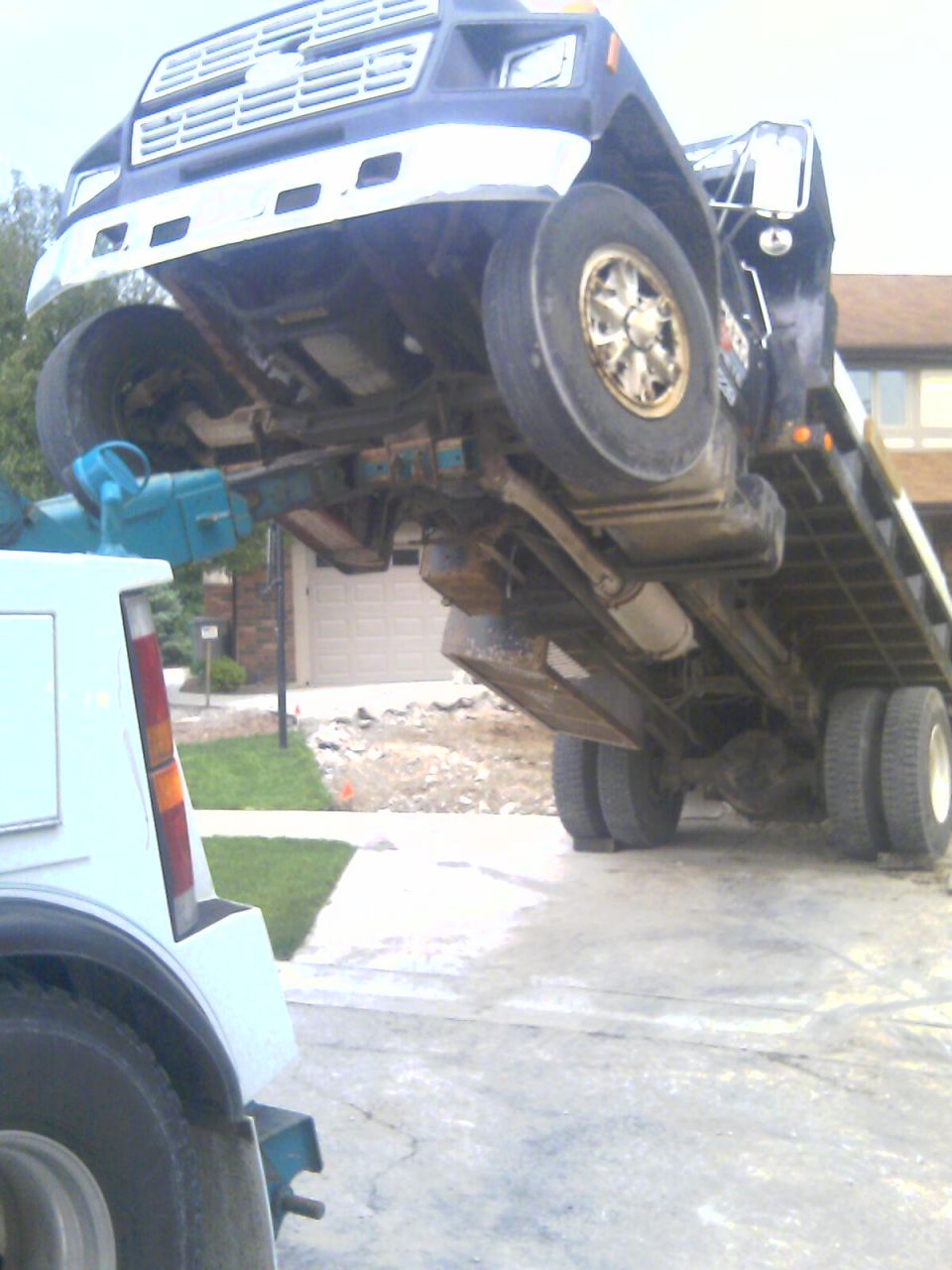 Tow truck lifting a blue truck chassis upside down