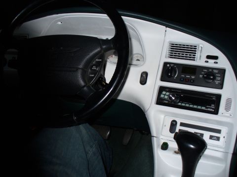 1995 Ford Thunderbird - The interior of a car features a white dashboard, a black steering wheel, and a multi-din stereo system.