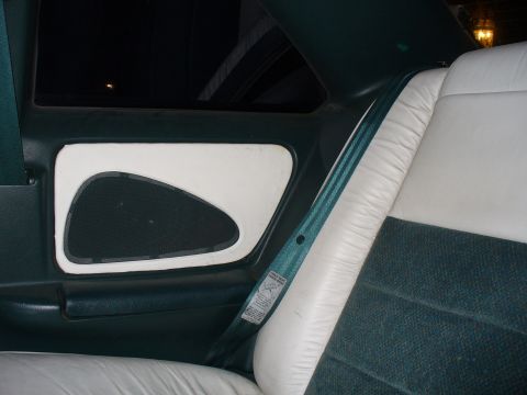 1995 Ford Thunderbird - The interior of a car features a teal seatbelt and white leather seats with dark green fabric inserts.