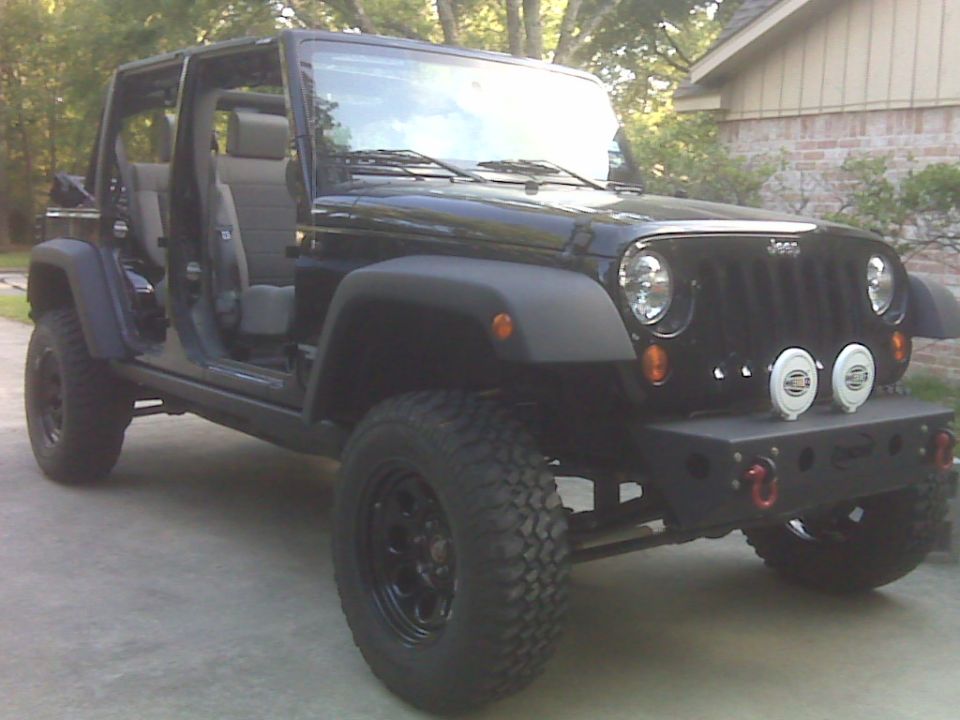 Black Jeep Wrangler with doors removed, aftermarket bumper, and off-road tires