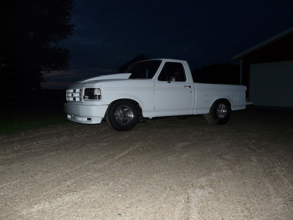 White Ford pickup at dusk on gravel with cowl hood and polished five-spoke wheels
