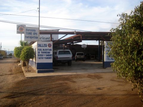 1996 Ford Bronco - A repair shop with two trucks parked under its covered area.