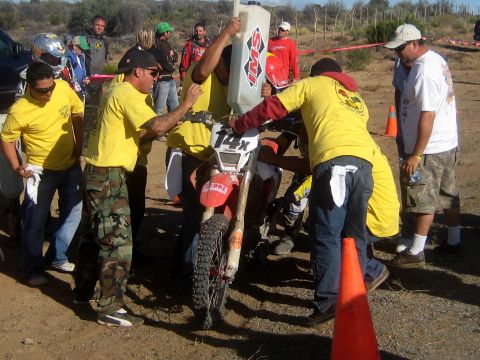 1996 Ford Bronco - A group of people in yellow shirts are refueling a dirt bike during an event.