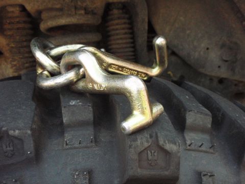1995 Ford Bronco - Close-up view of tow hooks and a chain resting on a tire, with visible suspension components in the background.