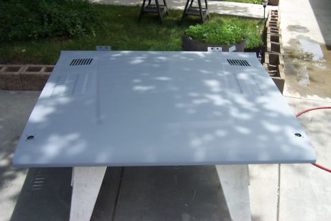 1976 Ford Bronco - A vehicle hood, primed and ready for paint, sits on sawhorses in an outdoor setting.