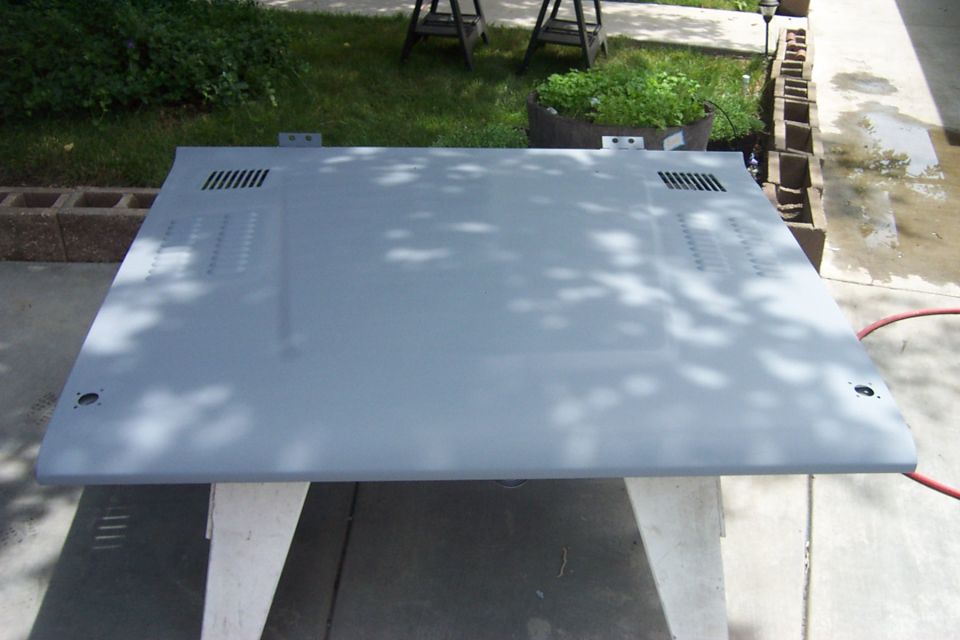 Gray primed hood on sawhorses outdoors. It has vents on the front corners