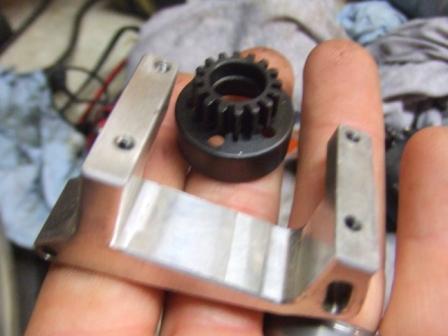 1996 Ford Bronco - A metal bracket and a black gear are held in a person's hand.